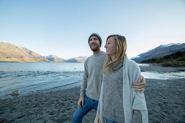 Happy couple standing on the shore of a lake near mountains