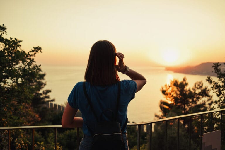 Woman looking at scenic orange sunset on the beach